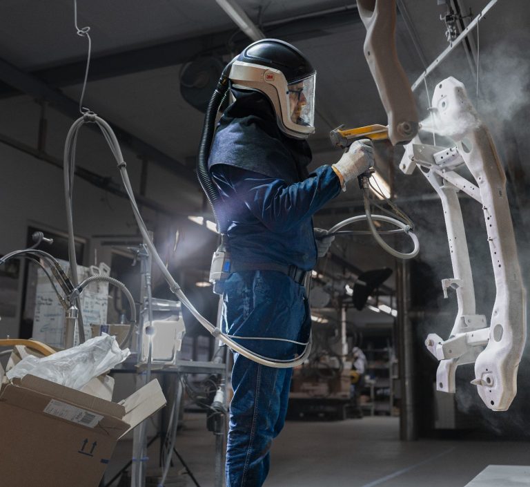 Businessporträts Foto eines Arbeiters in Schutzkleidung der Farbe auf einen Rahmen in einer Werkstatt sprüht.
